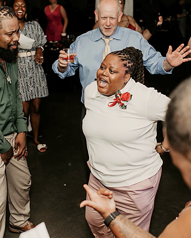 Wedding guests packed onto the dance floor mid-song, hands up and laughing.